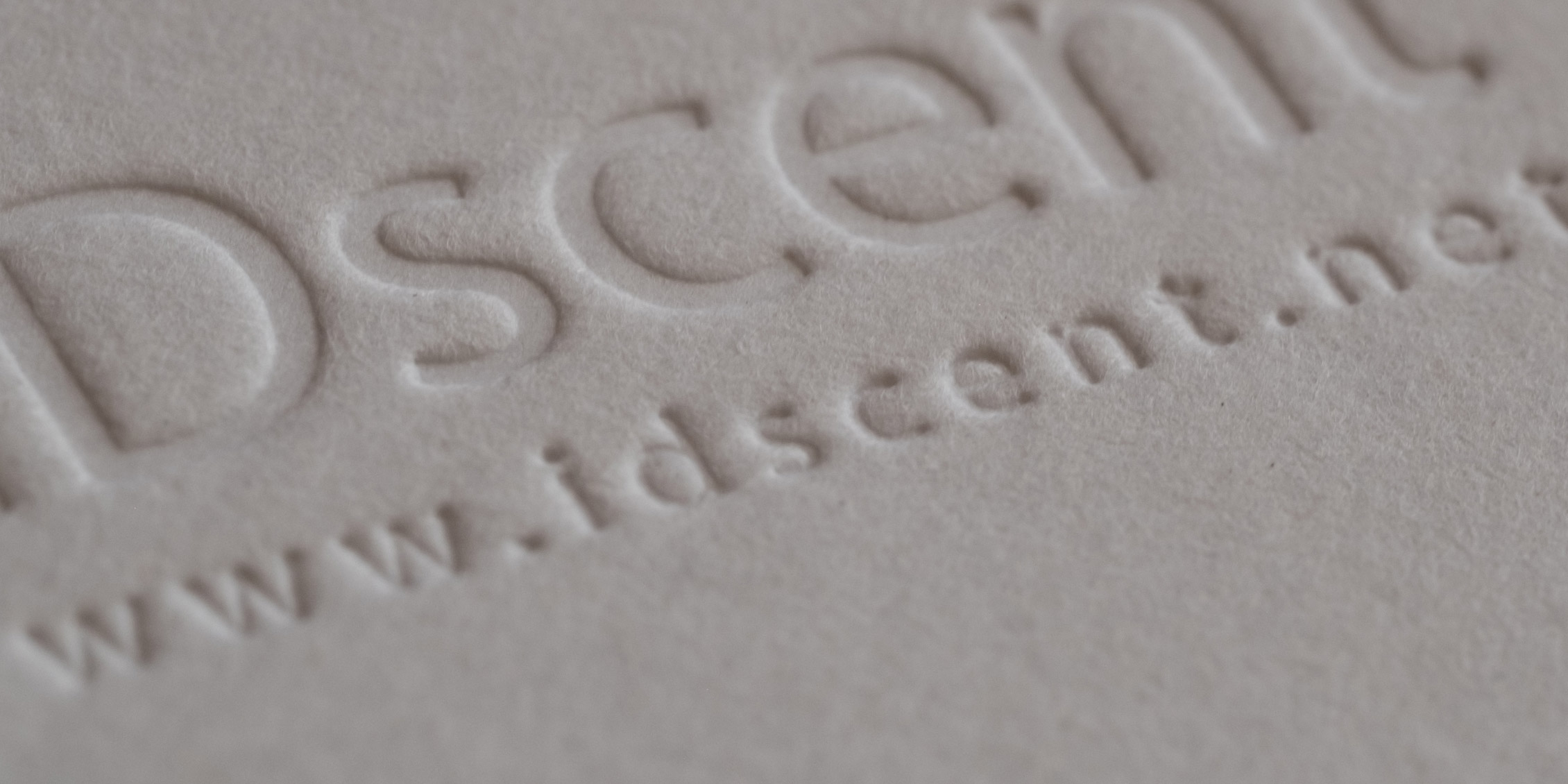 Détail macro du gaufrage du logo IDscént sur une carte olfactive